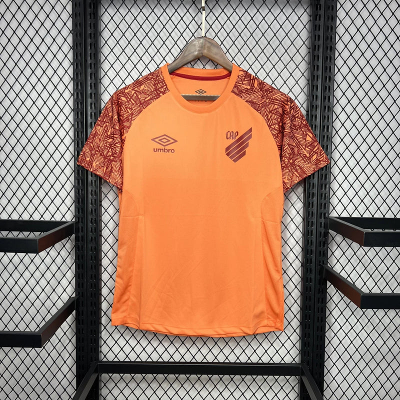 Camisa Athletico Paranaense Treino 2024/25 Umbro Torcedor Masculina laranja vibrante com escudo oficial bordado e logo Umbro estampado, modelo oficial de treino do clube paranaense.

