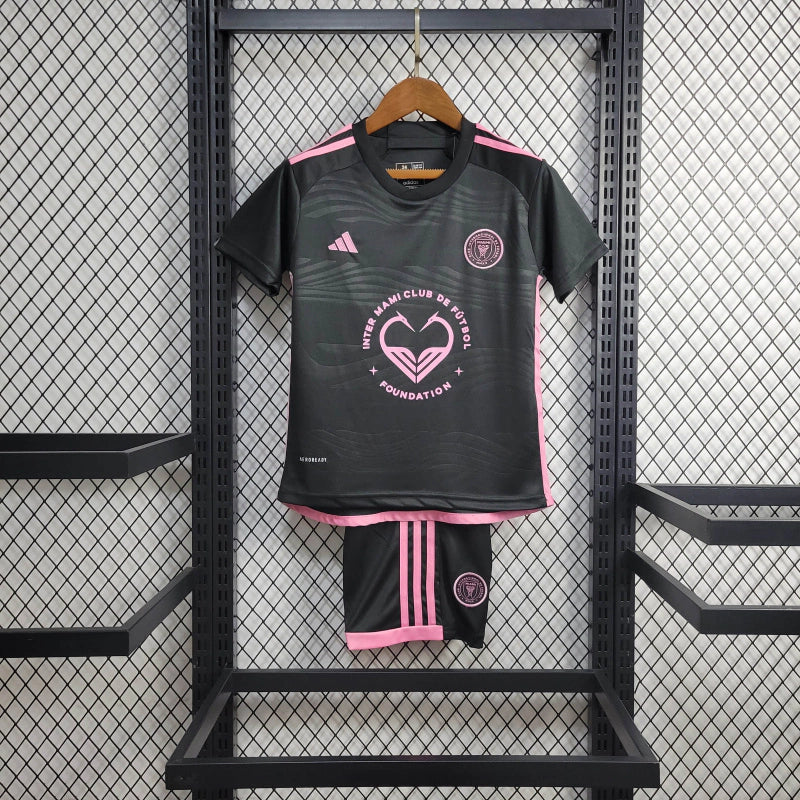 Kit Infantil Inter Miami Away 2024/25 Adidas – camisa rosa vibrante com detalhes em preto e shorts combinando, uniforme infantil oficial do Inter Miami, leve, respirável e confortável para crianças de 3 a 13 anos."