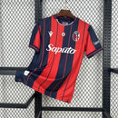 Camisa Bologna Home I 2025/26 Torcedor Masculina com listras verticais vermelhas e azuis, escudo bordado no peito, gola moderna e tecido leve, representando a tradição e a paixão do Bologna FC 1909.