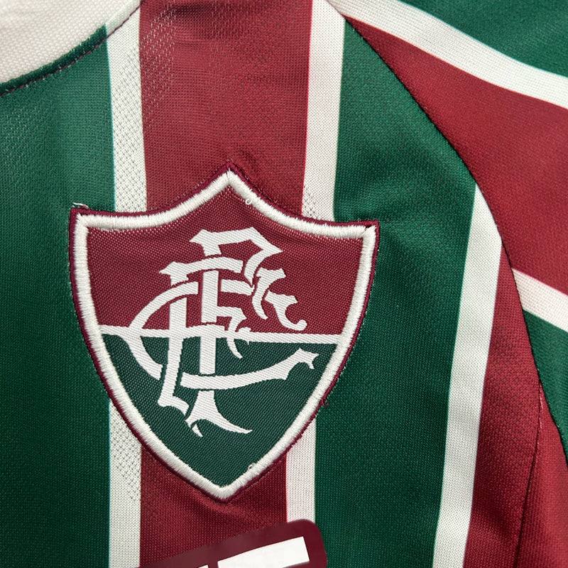 Kit Infantil Fluminense Home 2025/26 Umbro, camisa tricolor verde, grená e branca com shorts e meias combinando, uniforme oficial para crianças de 3 a 13 anos torcedoras do Fluminense."