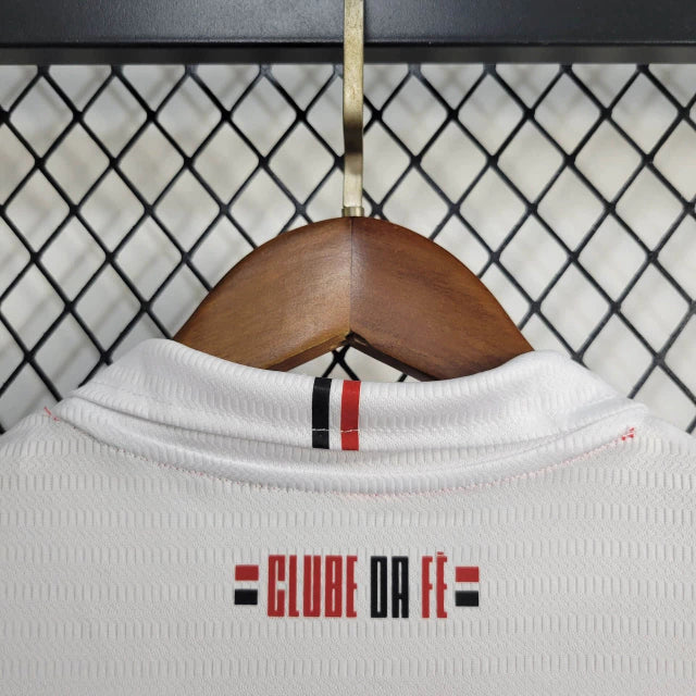 Kit Infantil São Paulo Home (1) 2024/25 New Balance oficial – camisa branca com listras vermelha, preta e branca, short e meião. Uniforme infantil do São Paulo FC temporada 2024/2025."