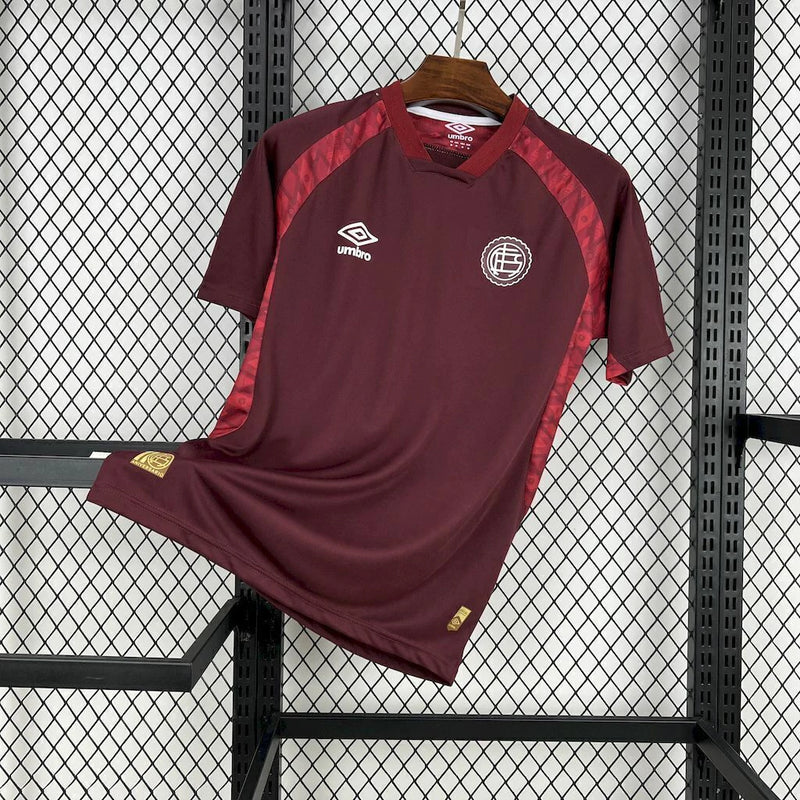 Camisa Lanús Home I 2025/26 Umbro Torcedor Masculina na cor vinho, modelo oficial para torcedores, com escudo do clube no peito e design clássico do time argentino."