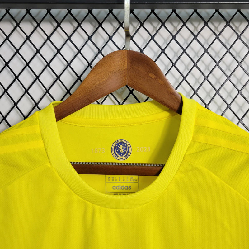 Camisa Escócia 150 Anos Adidas masculina na cor amarela, com detalhes em azul e branco, gola em V, mangas curtas e tecido respirável, edição comemorativa de 150 anos da seleção escocesa, ideal para torcedores"
