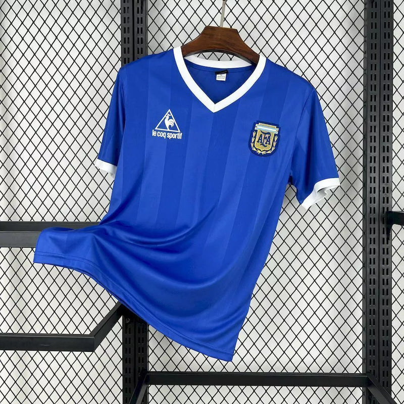 Camisa Argentina Away II 1986/87 Le Coq Sportif retrô masculina, azul escuro com detalhes em branco, escudo da AFA bordado no peito, gola clássica e mangas tradicionais, modelo histórico da seleção argentina após a Copa do Mundo de 1986.