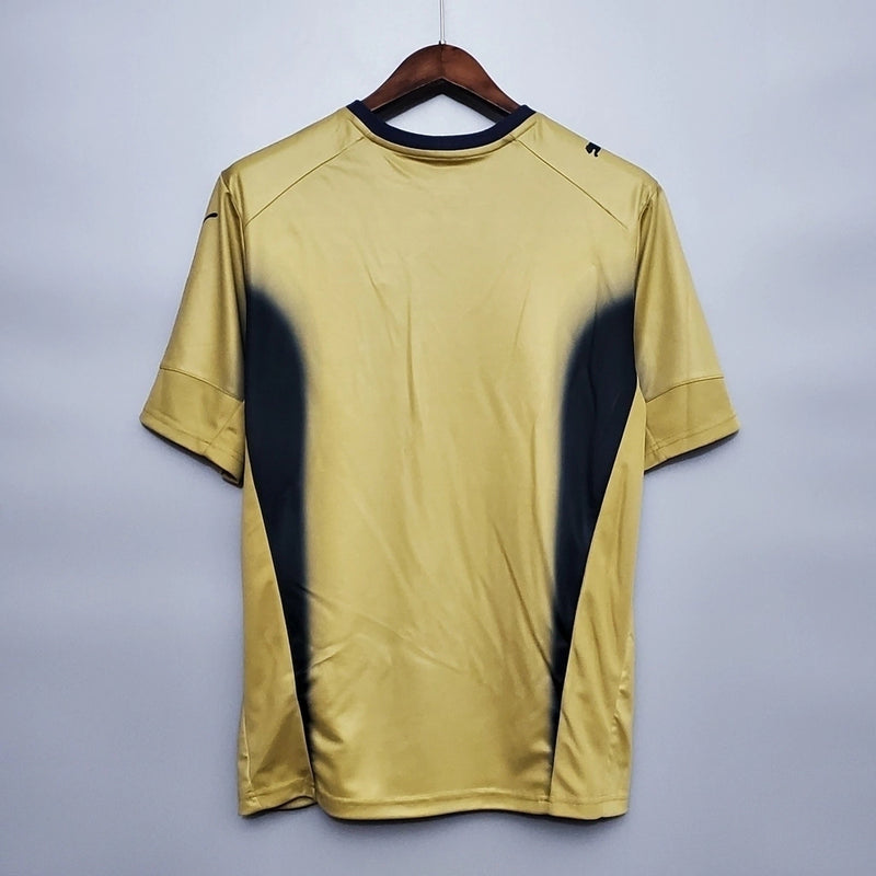 Camisa Itália Goleiro 2006/07 Puma Retrô masculina, dourada, com escudo da seleção italiana no peito e detalhes clássicos da temporada 2006/07, feita em tecido leve e confortável, ideal para colecionadores, fãs de futebol histórico e uso casual.”
