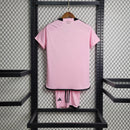 "Kit Infantil Inter Miami Home (1) 2024/25 Adidas oficial, camisa branca com detalhes em rosa e preto, escudo do Inter Miami CF em destaque, shorts e meias combinando, uniforme completo para crianças de 3 a 13 anos"