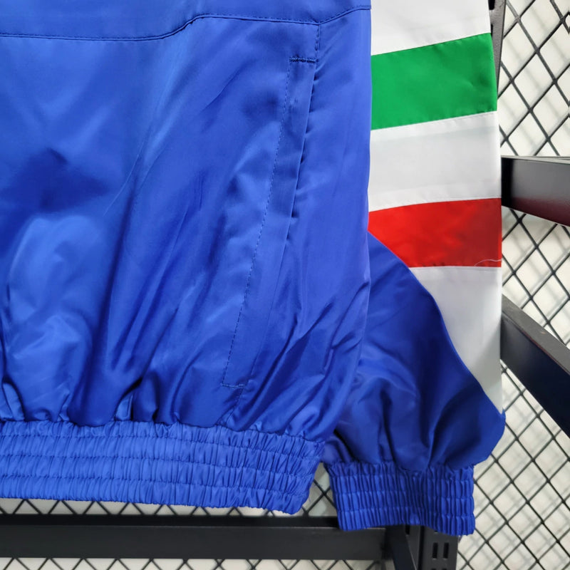Corta-Vento Itália Edição ICON 2023/24 Adidas Masculino, azul vibrante, com escudo da seleção italiana e logo Adidas em destaque, zíper frontal completo e bolsos funcionais, ideal para torcedores e uso casual.”