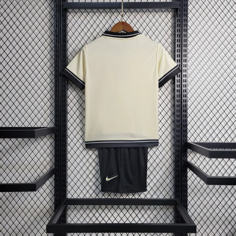 Kit Infantil Corinthians IV 2023/24 Nike, camisa preta com detalhes em branco, shorts e meias combinando, uniforme oficial do Timão para torcedores mirins."