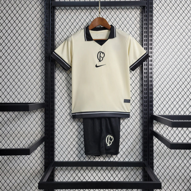 Kit Infantil Corinthians IV 2023/24 Nike, camisa preta com detalhes em branco, shorts e meias combinando, uniforme oficial do Timão para torcedores mirins."