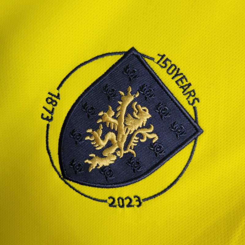 Camisa Escócia 150 Anos Adidas masculina na cor amarela, com detalhes em azul e branco, gola em V, mangas curtas e tecido respirável, edição comemorativa de 150 anos da seleção escocesa, ideal para torcedores"