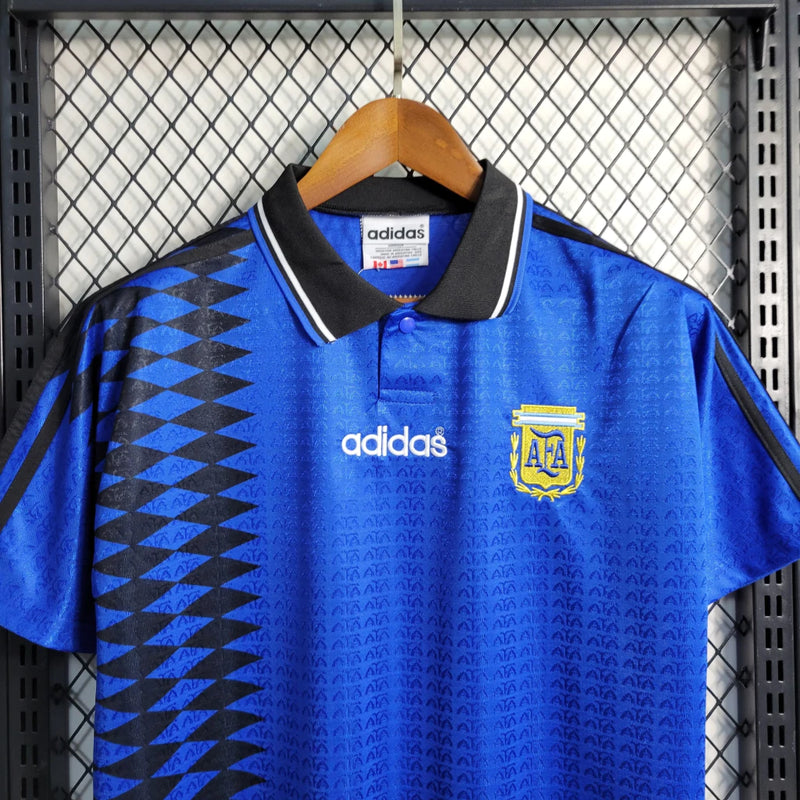 Camisa Argentina Away II 1994/95 Adidas Retrô Masculina azul com grafismos geométricos, escudo bordado da seleção e listras Adidas brancas nos ombros.