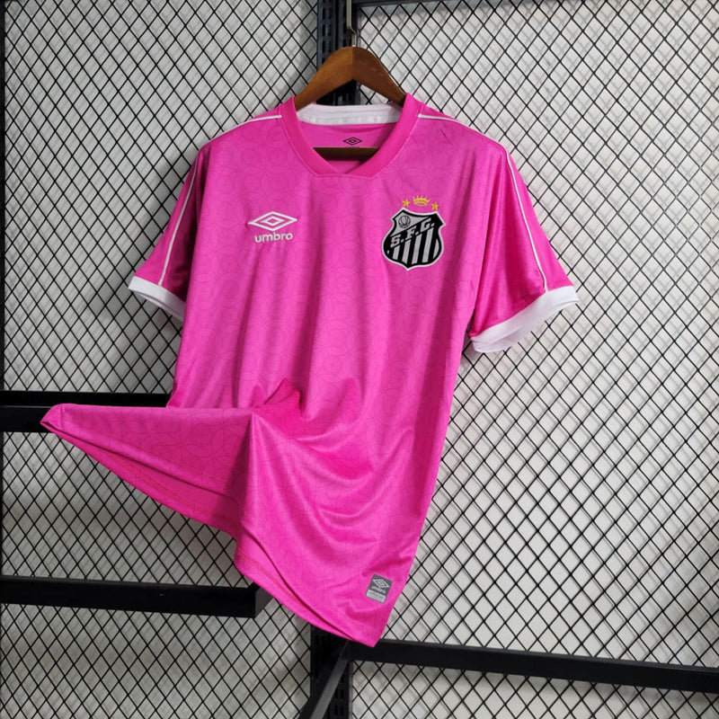 Imagem da Camisa Santos 2023/24 Umbro Torcedor Masculina na cor rosa, com escudo do Santos FC bordado no peito e detalhes em branco e preto.
