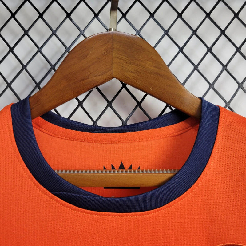 "Kit Infantil Holanda Home (1) 2024/25 Nike oficial, camisa laranja vibrante com escudo KNVB em destaque, shorts combinando, uniforme completo para crianças de 3 a 13 anos"