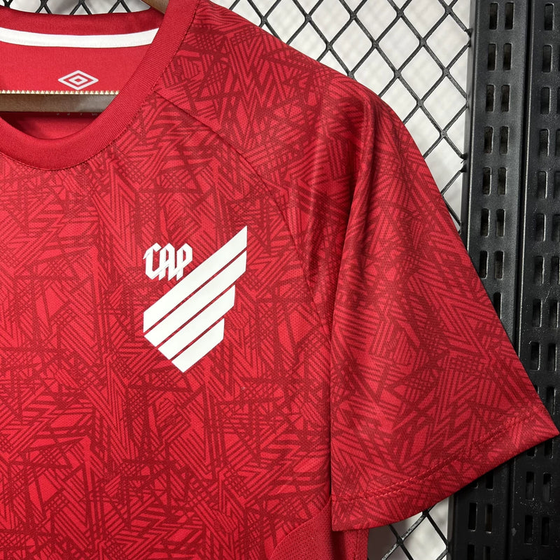 Camisa Athletico Paranaense Treino 2024/25 Umbro Torcedor Masculina com escudo oficial bordado e logo Umbro estampado, modelo masculino em tecido respirável para treino e uso casual.