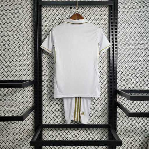 Kit Infantil Real Madrid Retrô 2011/12 Adidas oficial, camisa branca com escudo do Real Madrid em destaque, shorts e meias combinando, uniforme completo para crianças de 3 a 13 anos"