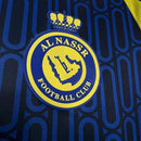 Camisa Al-Nassr Away (2) 2024/25 Adidas Torcedor Masculina branca com detalhes em azul e dourado, escudo do clube aplicado no peito e logo Adidas bordado."