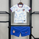 Kit Infantil Estados Unidos Home (1) 2025/26 Nike, uniforme oficial branco com detalhes em azul e vermelho, composto por camisa e shorts, disponível dos 3-4 aos 12-13 anos."