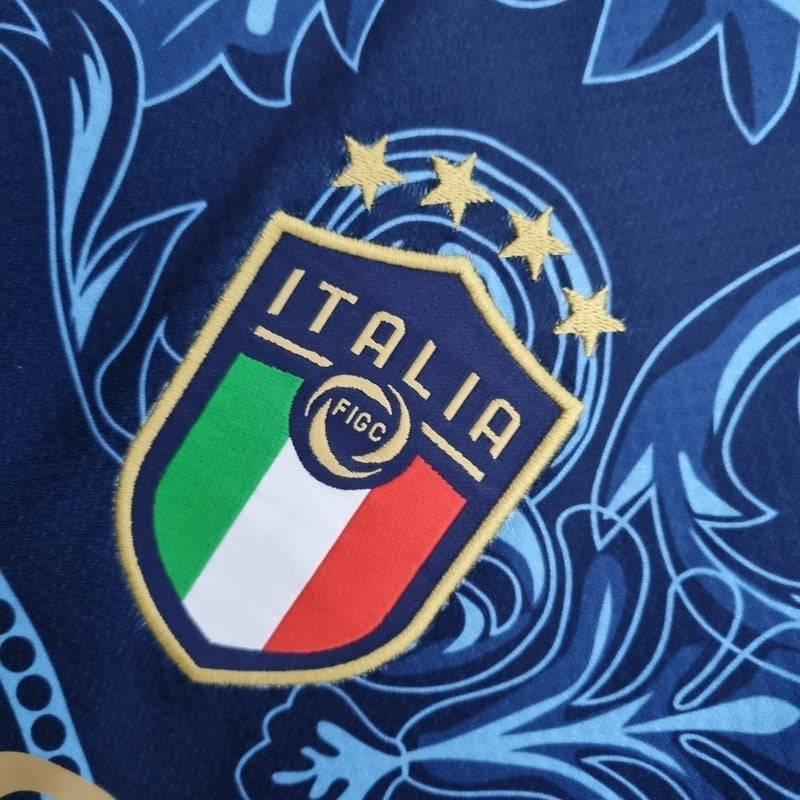 Camisa Concept Itália x Versace Puma Torcedor masculina, azul, com escudo da seleção italiana no peito, detalhes exclusivos da Versace e três listras Puma nos ombros, feita em tecido leve e respirável, modelo com caimento confortável, ideal para torcer com estilo e exclusividade.”