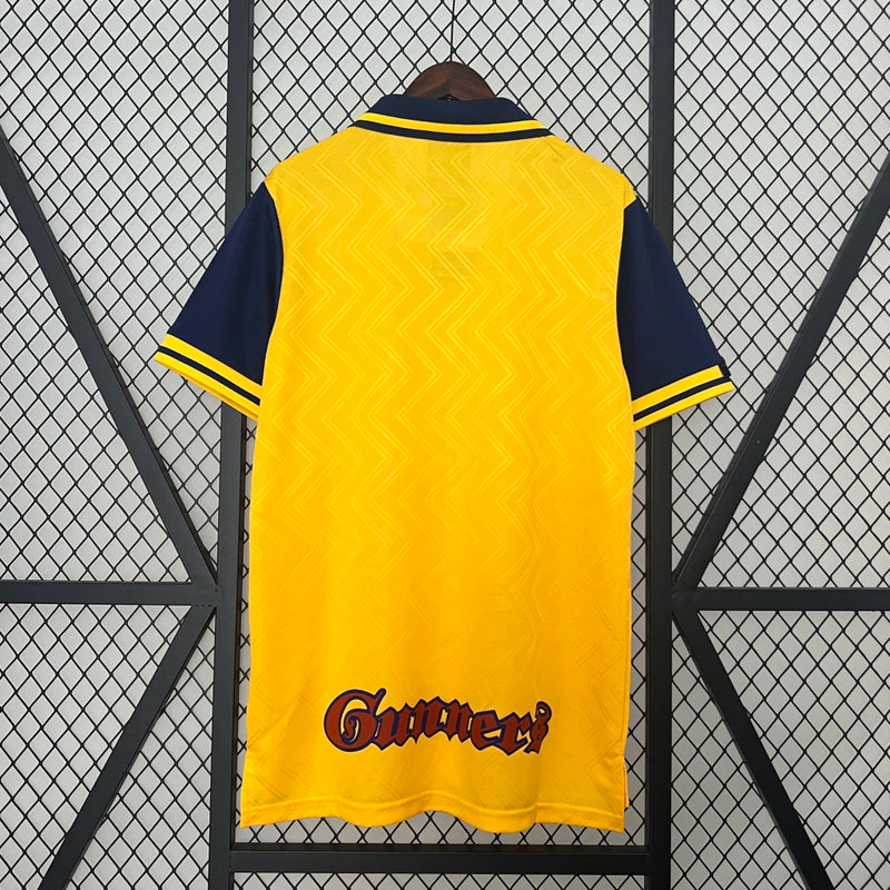 Camisa Arsenal Away II 1996/97 Nike Retrô Masculina amarela com detalhes em vermelho, gola clássica e escudo do Arsenal bordado, perfeita para colecionadores e fãs do futebol inglês."