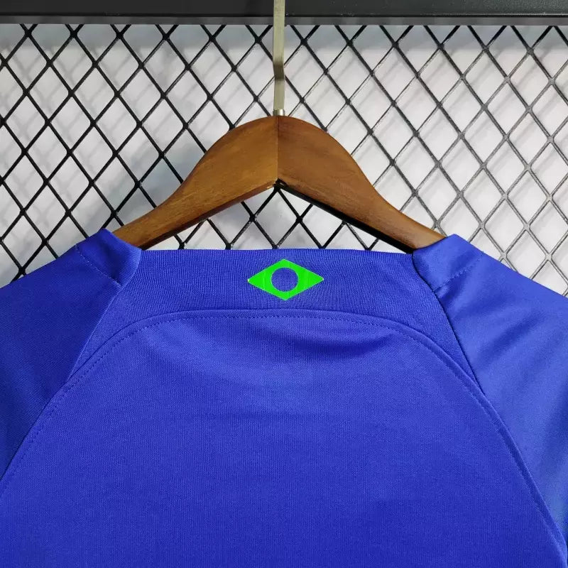 Kit Infantil Brasil Away 2022/23 Nike, camisa azul com detalhes em branco, shorts e meias combinando, uniforme oficial para crianças de 3 a 13 anos torcedoras da Seleção Brasileira."