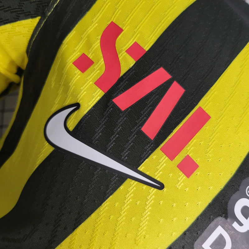 "Camisa Al-Ittihad Home I 2022/23 Nike Jogador Masculina na cor amarela com detalhes em preto, versão player slim fit, tecnologia Dri-FIT ADV, escudo em TPU premium – uniforme titular do Al-Ittihad Club da Arábia Saudita."