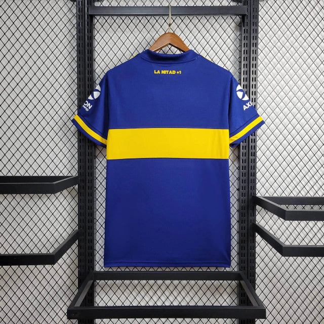 Texto alternativo para imagem:
Camisa Boca Juniors Home (1) 2020/21 Retrô Adidas Masculina azul com faixa amarela, escudo bordado e logo Adidas clássico estampado.

