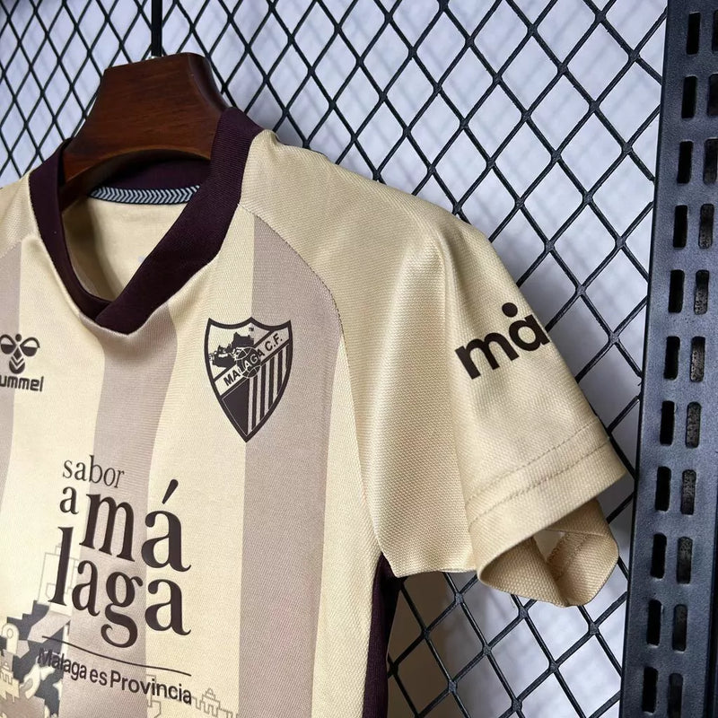 Kit Infantil Málaga CF Third III 2024/25 Hummel com camisa e short dourados, uniforme infantil leve e respirável, ideal para jogos, treinos e jovens torcedores do Málaga CF."