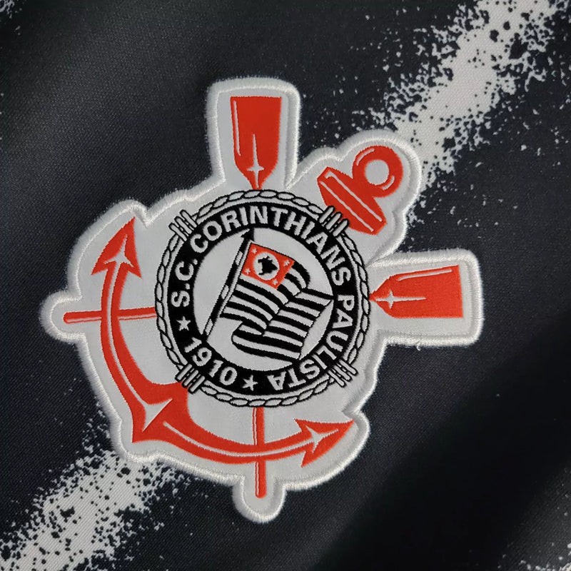 Camisa Corinthians Away 2021/22 Nike Torcedor Masculina na cor preta com listras verticais brancas, escudo bordado no peito e logo da Nike. Modelo pendurado em cabide sobre fundo metálico com grade.