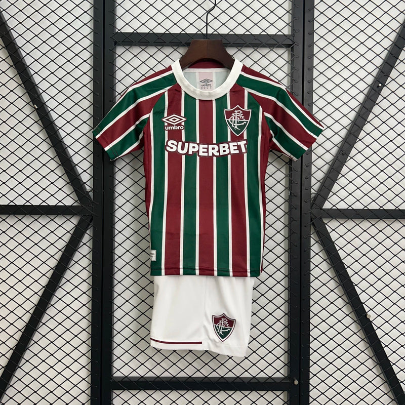 Kit Infantil Fluminense Home 2025/26 Umbro, camisa tricolor verde, grená e branca com shorts e meias combinando, uniforme oficial para crianças de 3 a 13 anos torcedoras do Fluminense."
