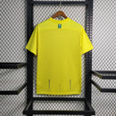 Camisa Al-Nassr Home (1) 2023/24 Nike Torcedor Masculina amarela com detalhes azuis, escudo do Al-Nassr e logo Nike bordados, modelo oficial usado por Cristiano Ronaldo."
