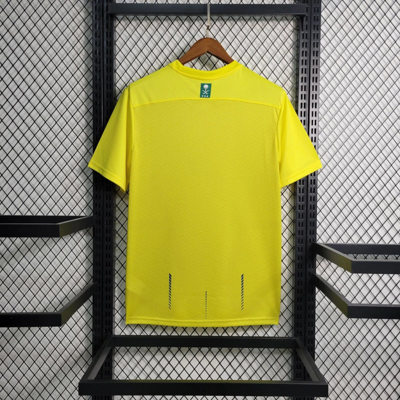 Camisa Al-Nassr Home (1) 2023/24 Nike Torcedor Masculina amarela com detalhes azuis, escudo do Al-Nassr e logo Nike bordados, modelo oficial usado por Cristiano Ronaldo."
