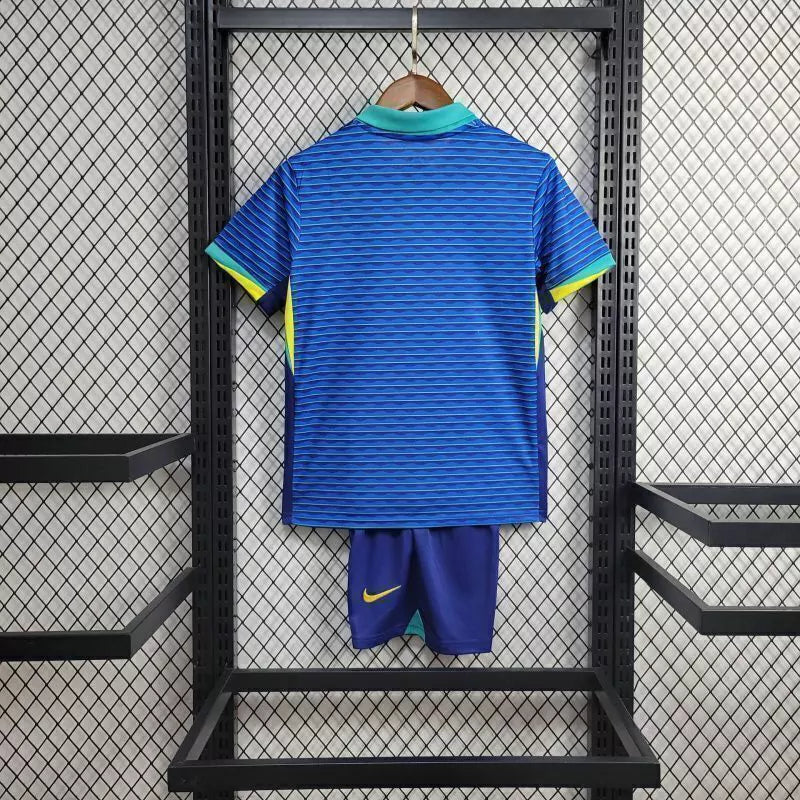 "Kit Infantil Brasil Away 2024/25 Nike, camisa azul com detalhes em verde e amarelo, shorts e meias combinando, uniforme oficial da Seleção Brasileira para torcedores mirins."