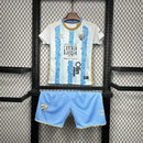 Kit Infantil Málaga CF Home I 2024/25 Hummel com camisa e short, uniforme infantil azul, tecido leve e respirável, ideal para jogos, treinos e jovens torcedores do Málaga CF."