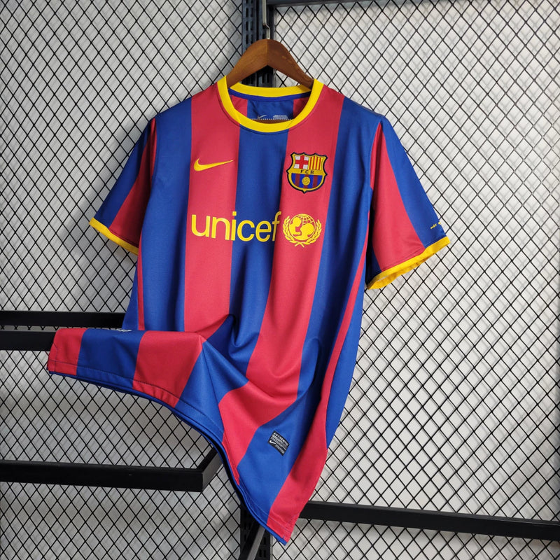"Camisa Barcelona 2010/11 Nike Masculina, close no escudo oficial do FC Barcelona aplicado no peito, peça icônica azul e grená."