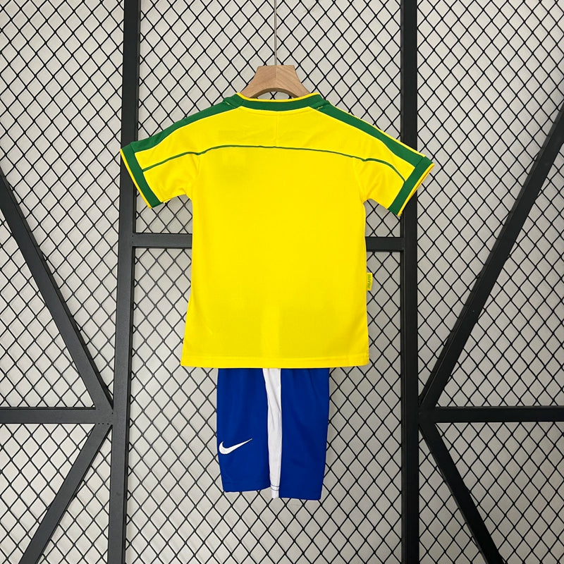 Kit Infantil Brasil Home 1998/99 Nike, camisa amarela com detalhes verdes, shorts e meias combinando, uniforme retrô oficial para crianças de 3 a 13 anos torcedoras da Seleção Brasileira."