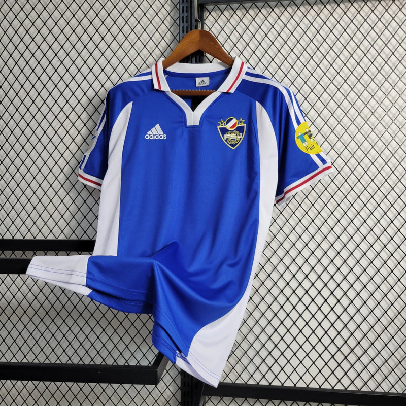 Camisa Iugoslávia 2000/01 Adidas retrô masculina azul com detalhes em branco e vermelho, gola polo com botão e mangas curtas, modelo clássico em tecido leve para torcedores e colecionadores"