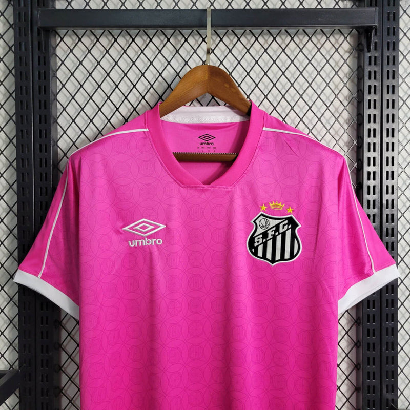 Imagem da Camisa Santos 2023/24 Umbro Torcedor Masculina na cor rosa, com escudo do Santos FC bordado no peito e detalhes em branco e preto.