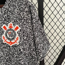 Camisa Corinthians 2023/24 Edição Especial Nike Torcedor Masculina com estampa preta e branca estilo caderno universitário, escudo bordado e logo Nike vermelho, pendurada em cabide contra uma grade metálica.