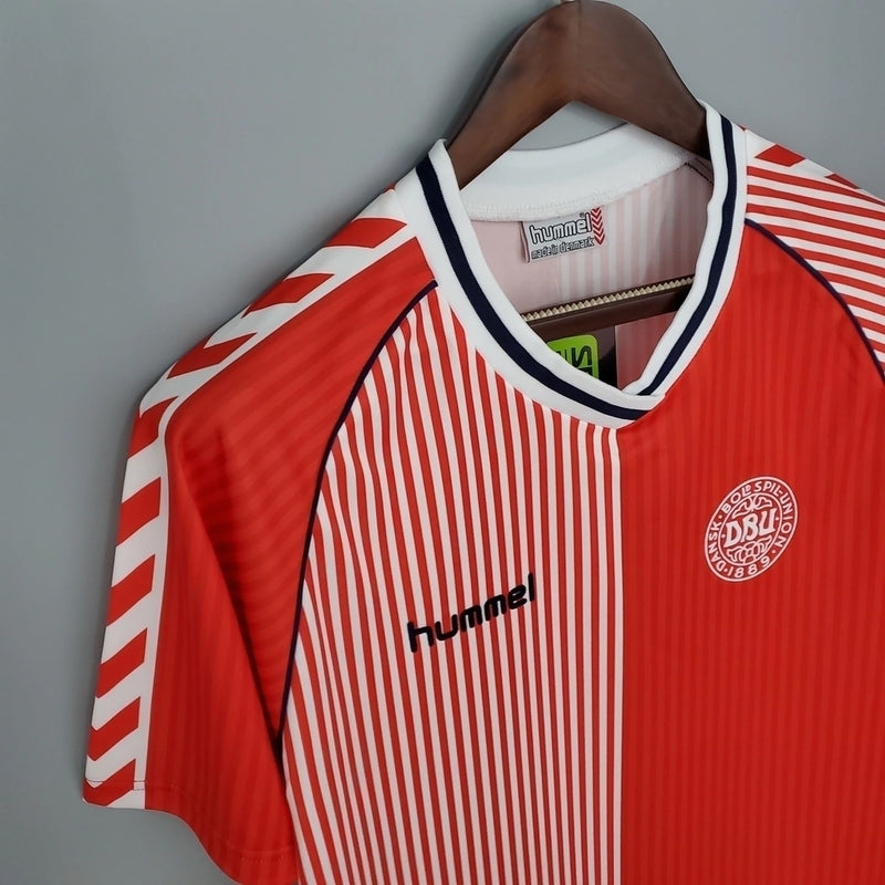 Camisa Dinamarca Home I 1986/87 Hummel Retrô Masculina, vermelha, com escudo da seleção dinamarquesa e logo Hummel bordados, feita em tecido leve e confortável, modelo retrô masculino com caimento tradicional, ideal para colecionadores e uso casual.”