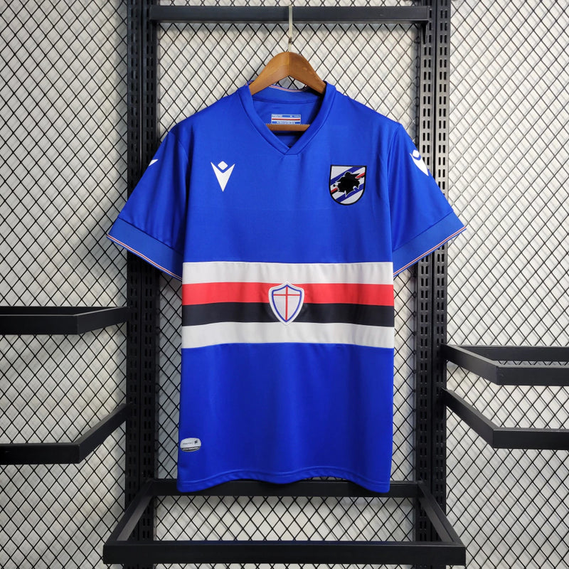 Camisa Sampdoria Home I 2022/23 Torcedor Masculina Azul com faixas branca, vermelha e preta no peito, escudo bordado e design clássico do clube italiano.”
