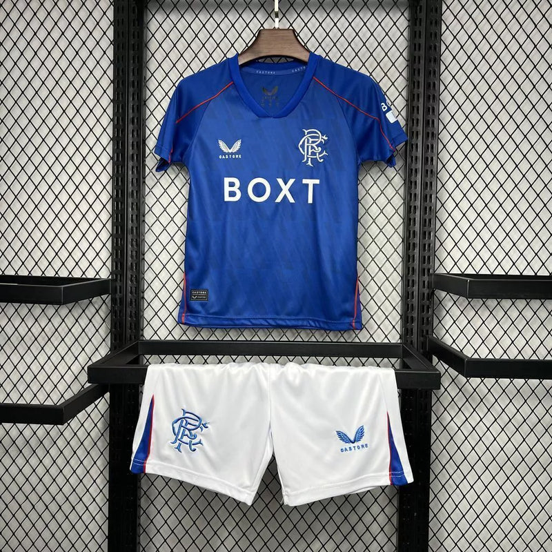 Kit Infantil Rangers FC Home (1) 2024/25 Castore completo com camisa azul, shorts e meias, escudo do clube em destaque, design moderno e confortável para crianças de 3 a 13 anos"