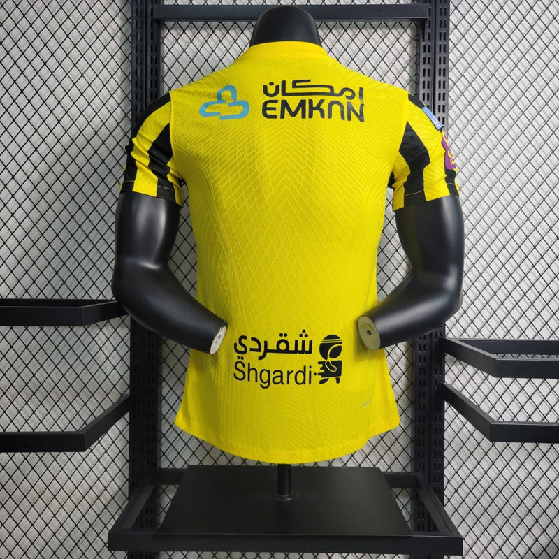 "Camisa Al-Ittihad Home I 2022/23 Nike Jogador Masculina na cor amarela com detalhes em preto, versão player slim fit, tecnologia Dri-FIT ADV, escudo em TPU premium – uniforme titular do Al-Ittihad Club da Arábia Saudita."