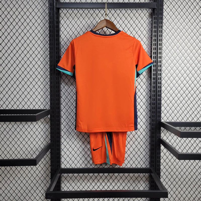 "Kit Infantil Holanda Home (1) 2024/25 Nike oficial, camisa laranja vibrante com escudo KNVB em destaque, shorts combinando, uniforme completo para crianças de 3 a 13 anos"