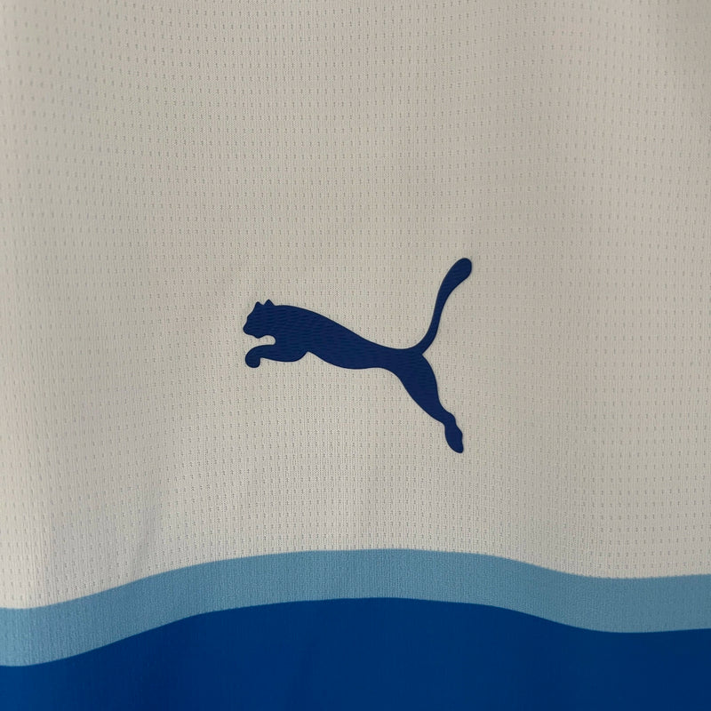 Camisa Universidad Católica Home I 2024/25 Puma Torcedor Masculina branca, uniforme de futebol chileno com detalhes azuis, escudo da Católica em destaque e tecnologia DryCell para conforto e absorção de suor.