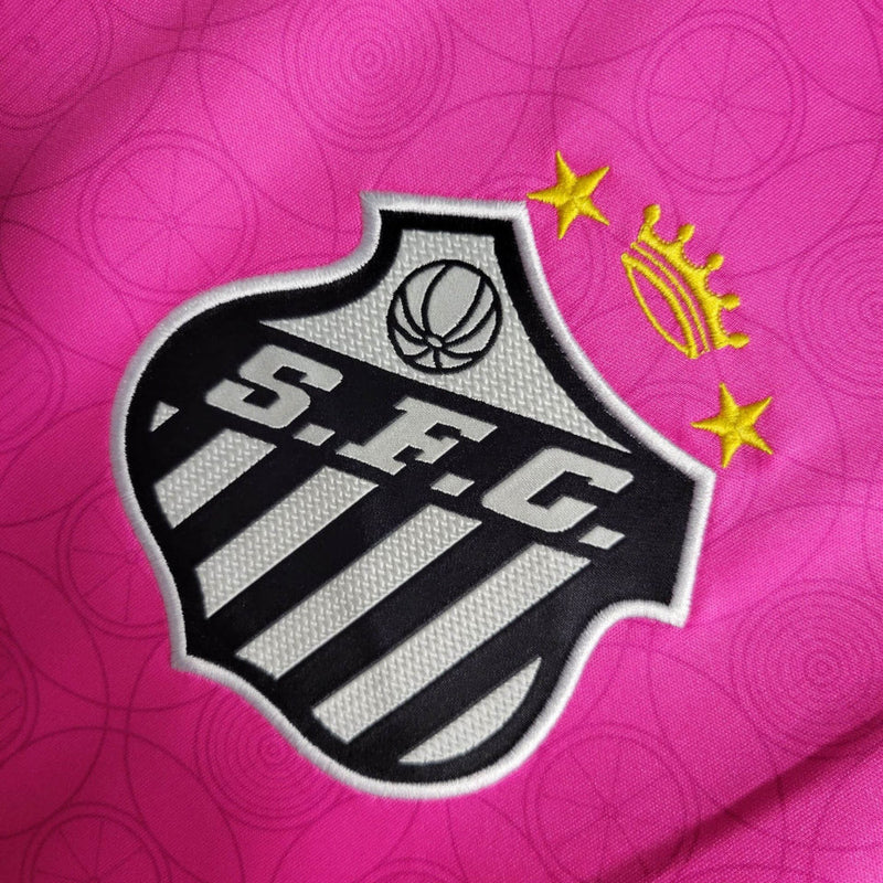 Imagem da Camisa Santos 2023/24 Umbro Torcedor Masculina na cor rosa, com escudo do Santos FC bordado no peito e detalhes em branco e preto.