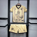 Kit Infantil Málaga CF Third III 2024/25 Hummel com camisa e short dourados, uniforme infantil leve e respirável, ideal para jogos, treinos e jovens torcedores do Málaga CF."