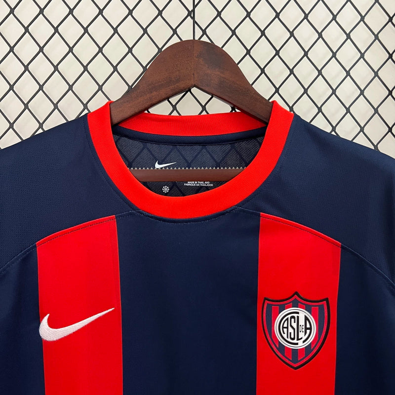 "Camisa San Lorenzo Home I 2024/25 Nike Torcedor Masculina azul com listras vermelhas, escudo estampado do clube argentino e design clássico azulgrana."