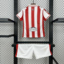 Kit Infantil Sporting Gijón Home (1) 2025/26 Puma, camisa listrada vermelha e branca com shorts oficiais, disponível dos tamanhos 3-4 anos até 12-13 anos, ideal para pequenos torcedores."