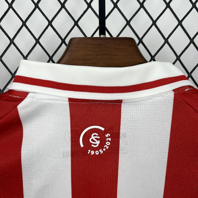Kit Infantil Sporting Gijón Home (1) 2025/26 Puma, camisa listrada vermelha e branca com shorts oficiais, disponível dos tamanhos 3-4 anos até 12-13 anos, ideal para pequenos torcedores."