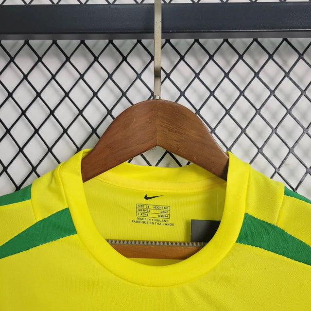 Kit Infantil Brasil Home 2002 Nike Retrô – uniforme completo com camisa amarela, shorts azul e meião branco, inspirado no penta da Copa do Mundo, confortável e ideal para crianças apaixonadas por futebol."
